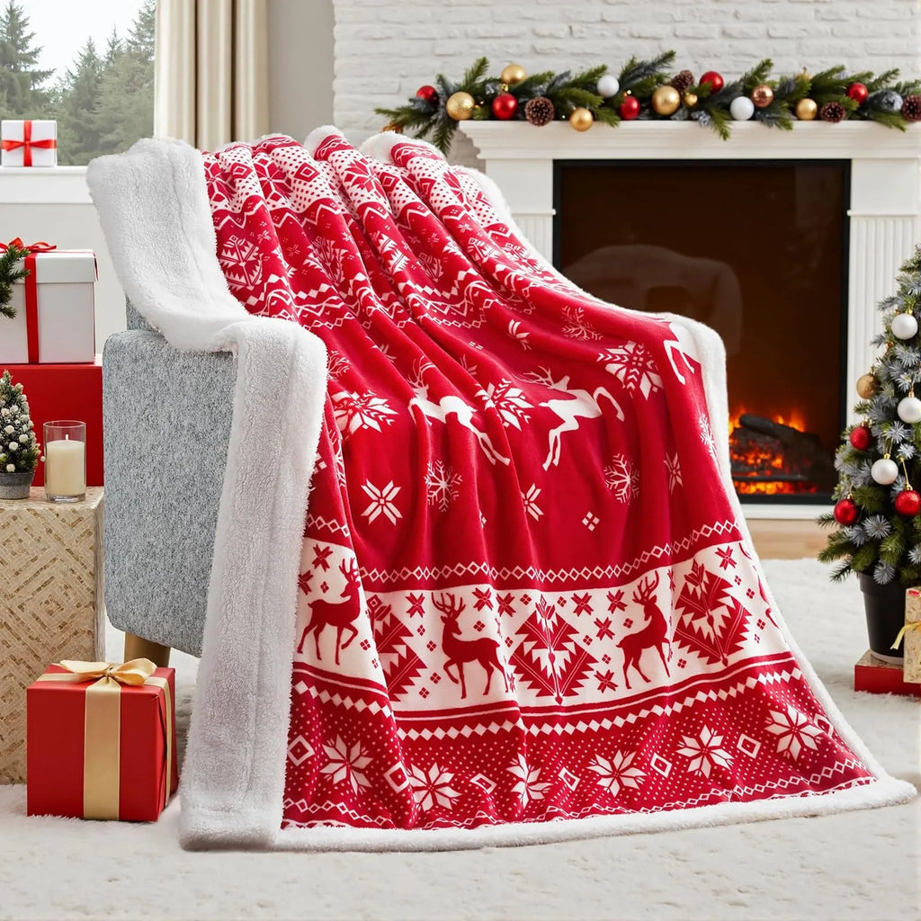 Soft red polyester flannel Christmas blanket with festive pattern draped over a bed