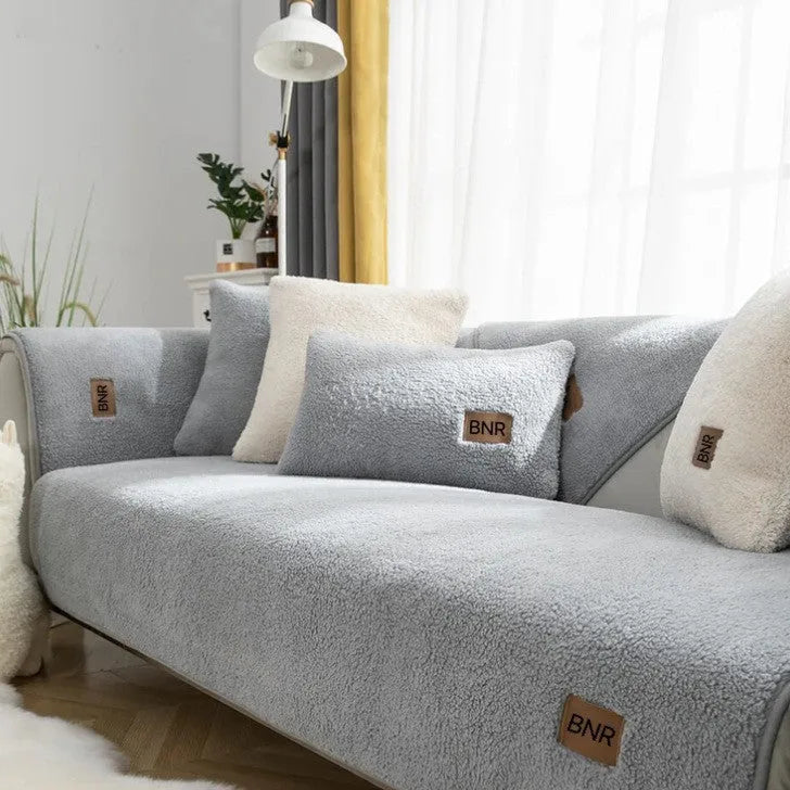 Lambswool-style solid colour sofa cover and pillow on a grey sofa.