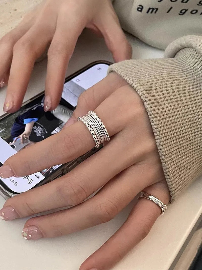 Close-up of a copper ring with a woven twisted geometric multilayer design on a model's hand.