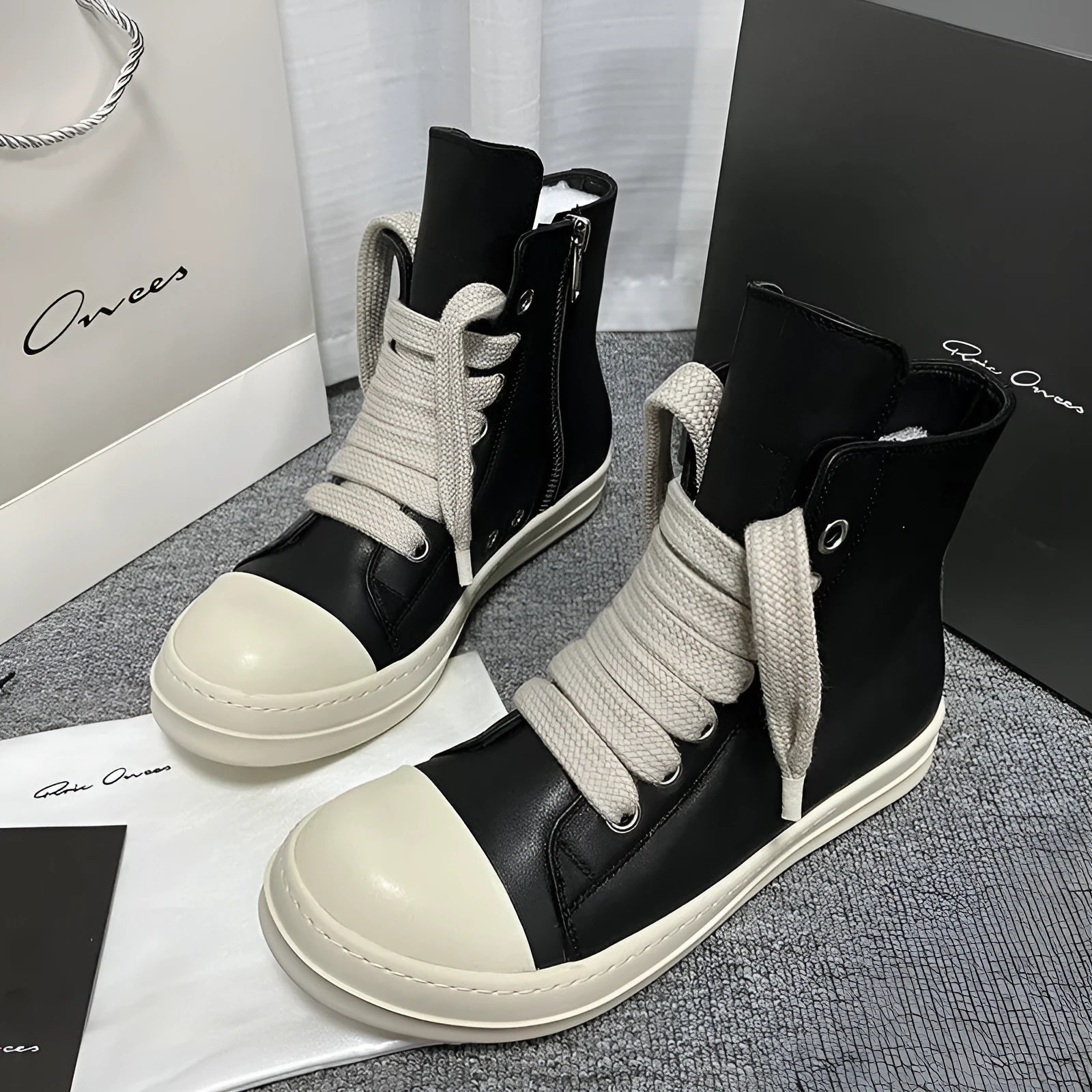 Black high-top leather unisex sneakers with a side zipper on a white background.