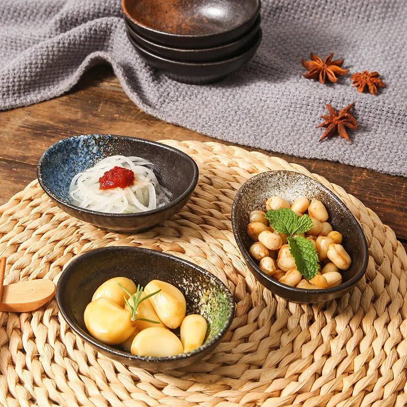 Oval Japanese ceramic sauce dipping bowl with traditional underglaze pattern on a wooden table.