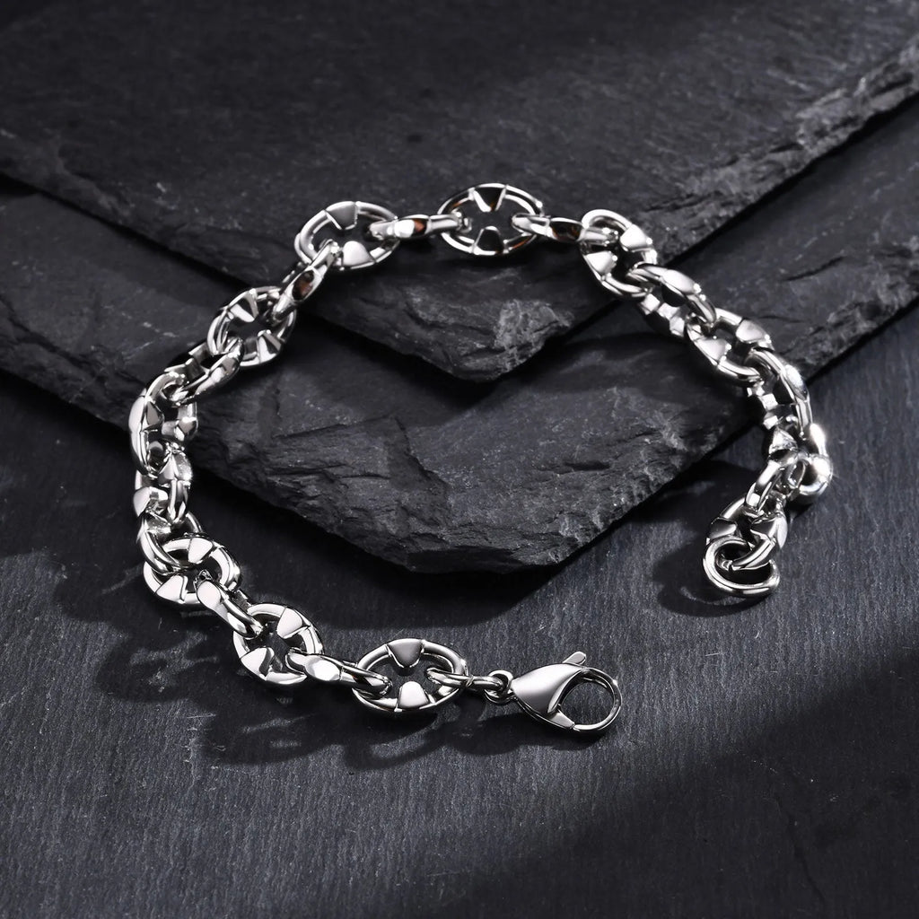 A thick geometric chain bracelet made from stainless steel in a steel colour, shown on a wrist.