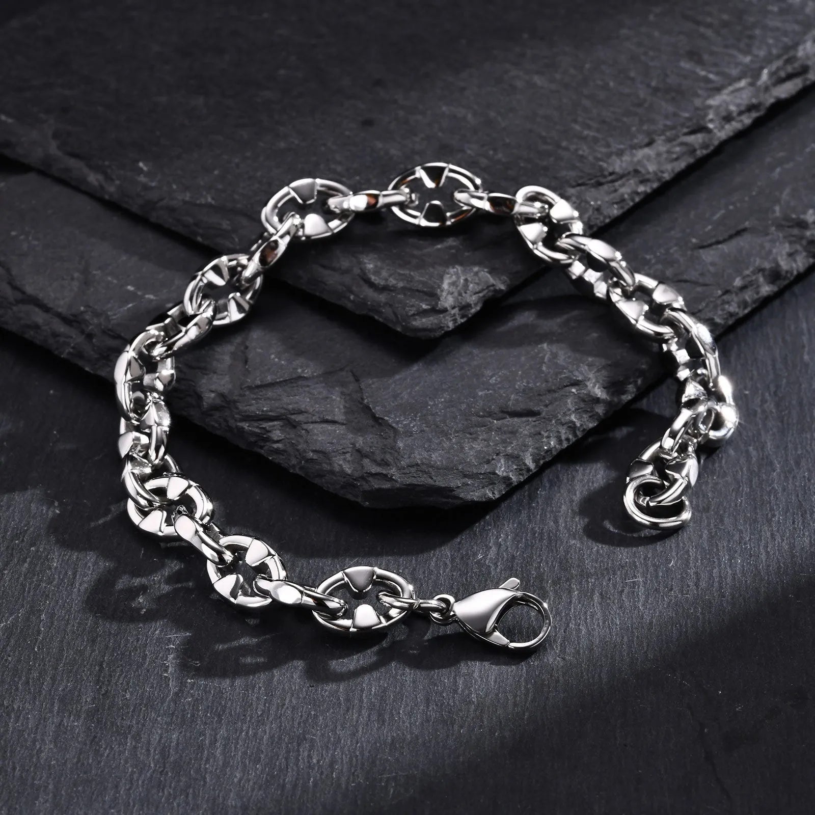 A thick geometric chain bracelet made from stainless steel in a steel colour, shown on a wrist.