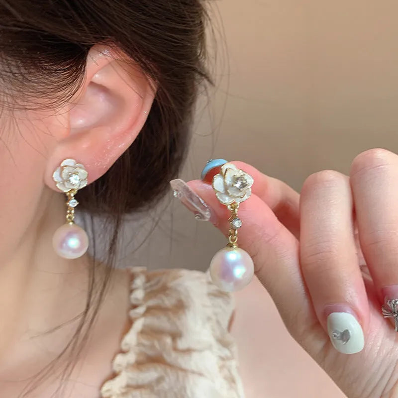 A pair of camellia flower design stud earrings for women in a pearl-white alloy.
