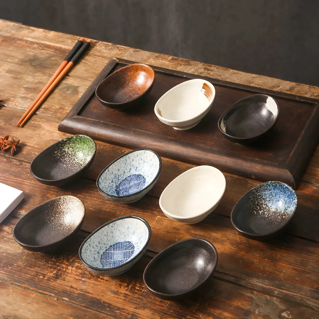 Oval Japanese ceramic sauce dipping bowl with traditional underglaze pattern on a wooden table.
