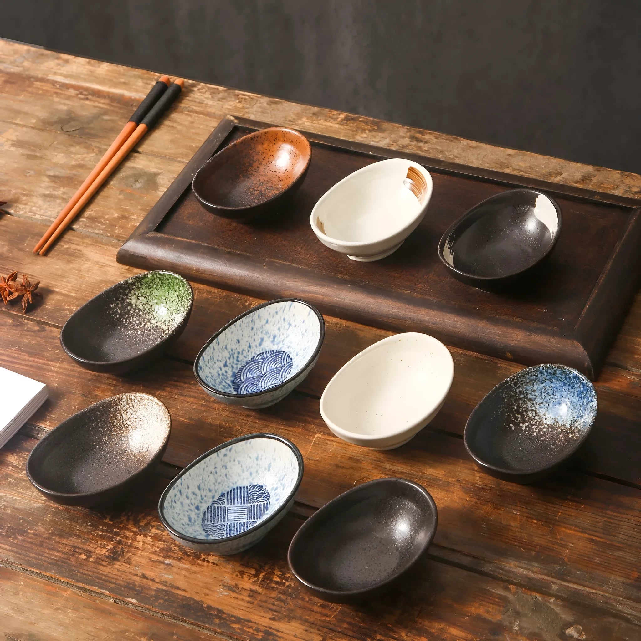 Oval Japanese ceramic sauce dipping bowl with traditional underglaze pattern on a wooden table.
