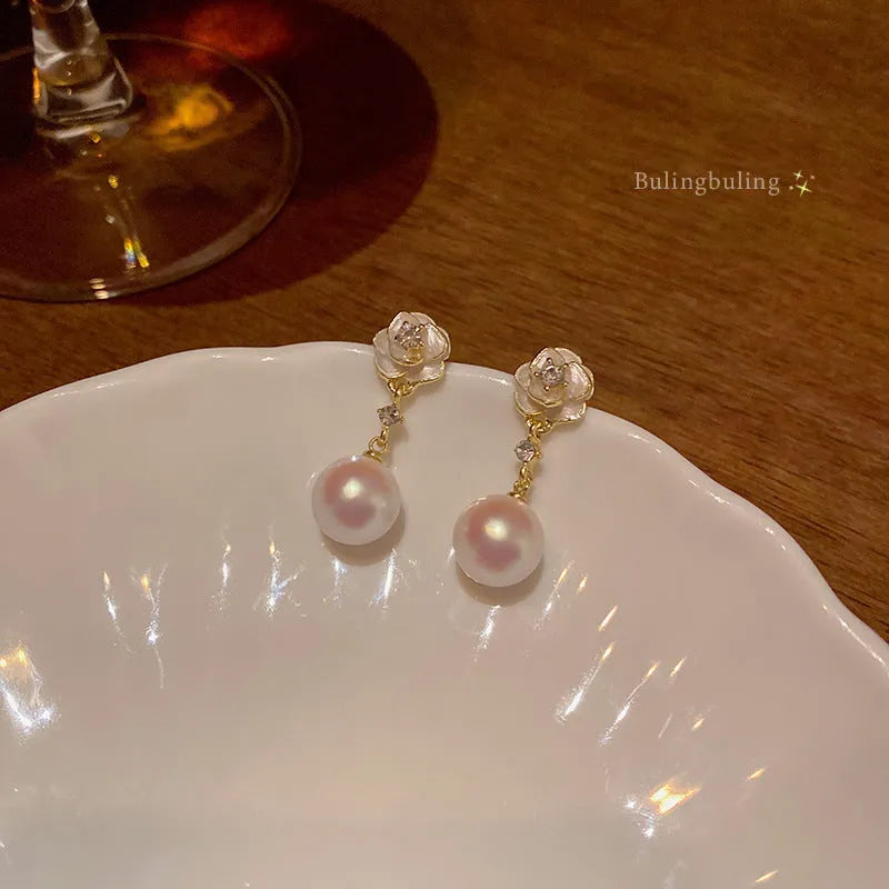A pair of camellia flower design stud earrings for women in a pearl-white alloy.