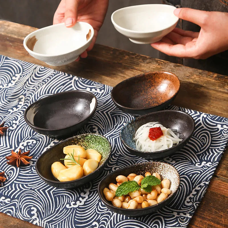 Oval Japanese ceramic sauce dipping bowl with traditional underglaze pattern on a wooden table.