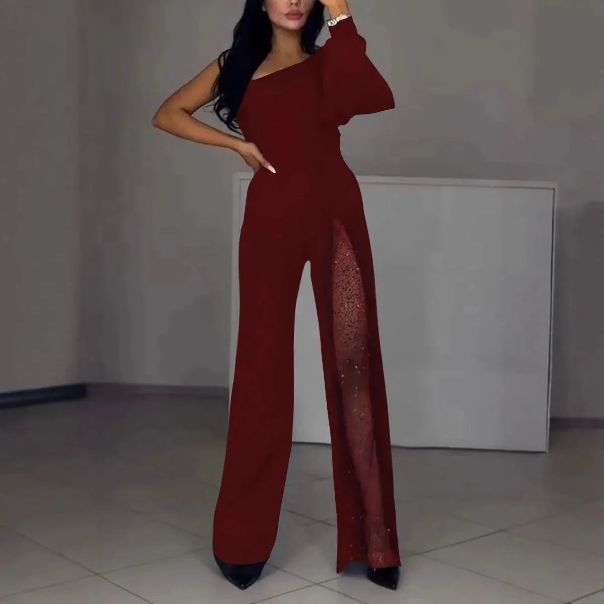 Black women's jumpsuit with an oblique shoulder design and a high slit on the leg.