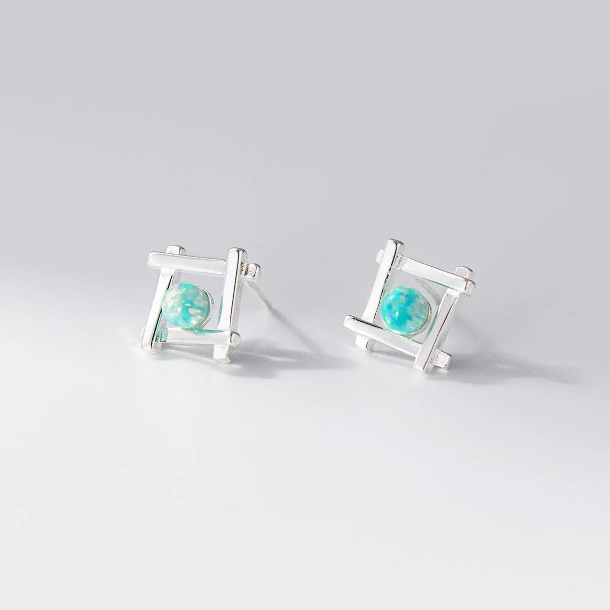 Geometric cross-shaped silver stud earrings for women on a white background.