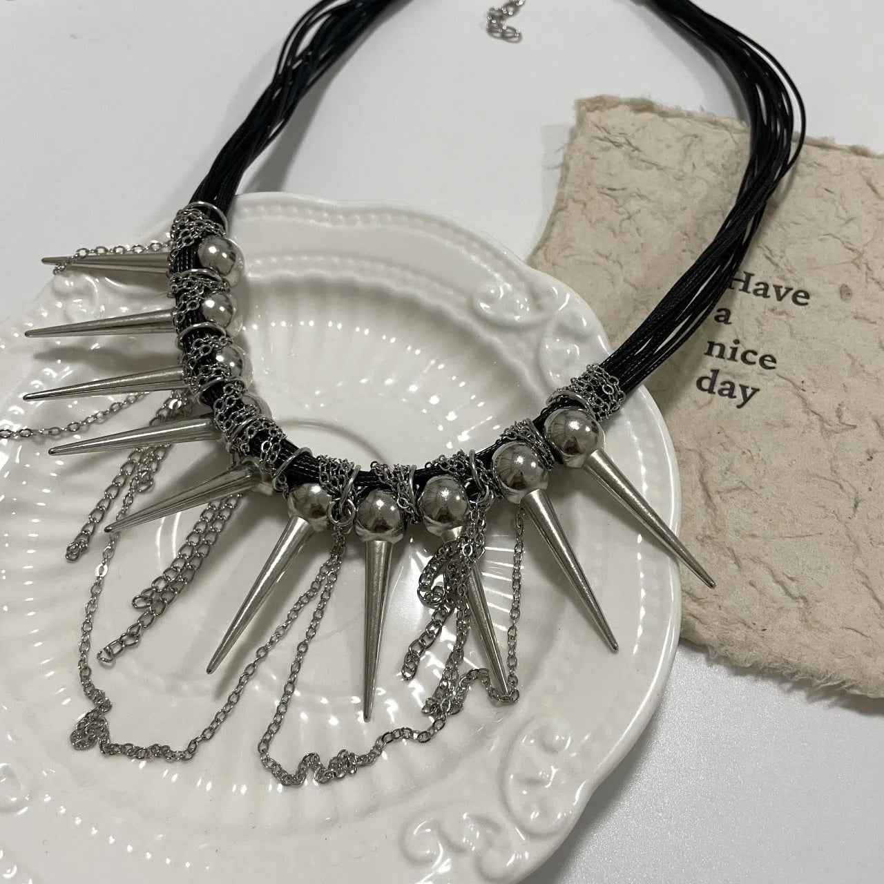 Leather necklace with winding round beads, tassel detail, and electroplated point rivets in casual style.