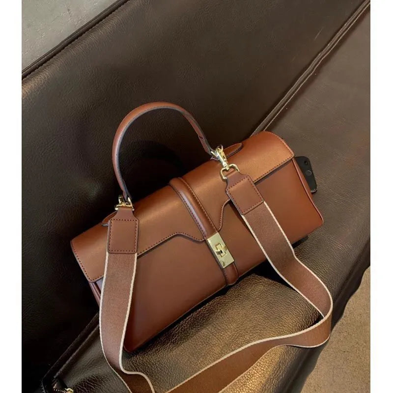 Women's solid colour cowhide leather messenger bag in black, cylindrical shape, with crossbody strap