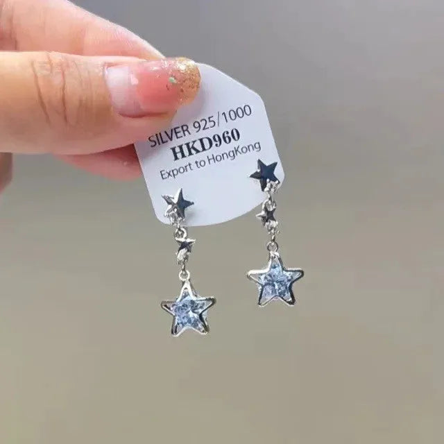 Silver geometric heart-shaped clip-on earrings with rhinestones and a dangling star tassel charm.
