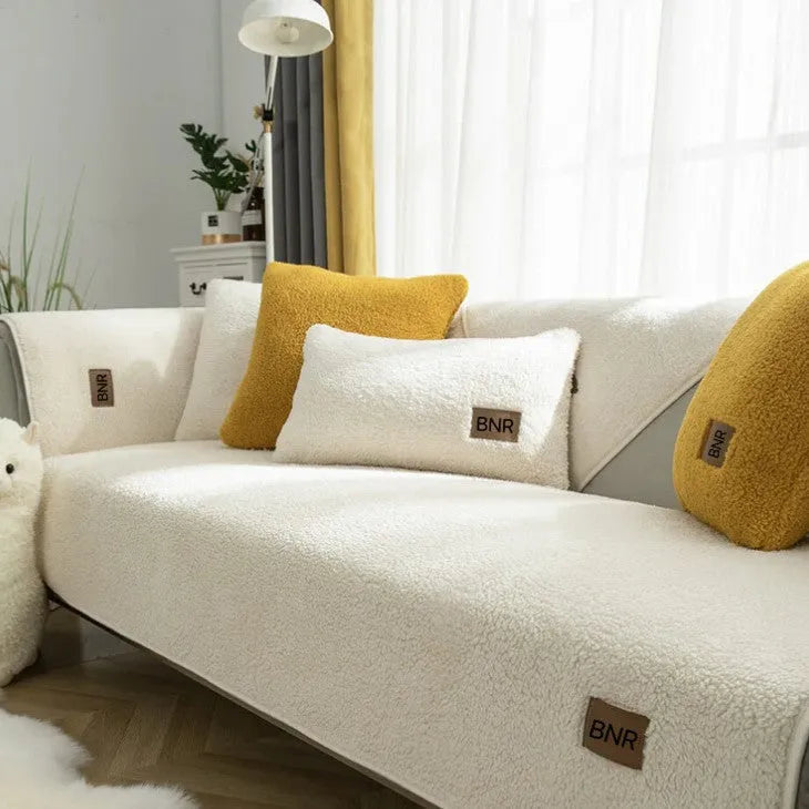 Lambswool-style solid colour sofa cover and pillow on a grey sofa.