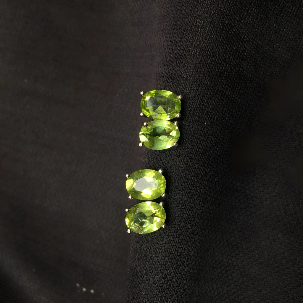 Natural grass green olivine faceted stud earrings in S925 sterling silver on a white background.
