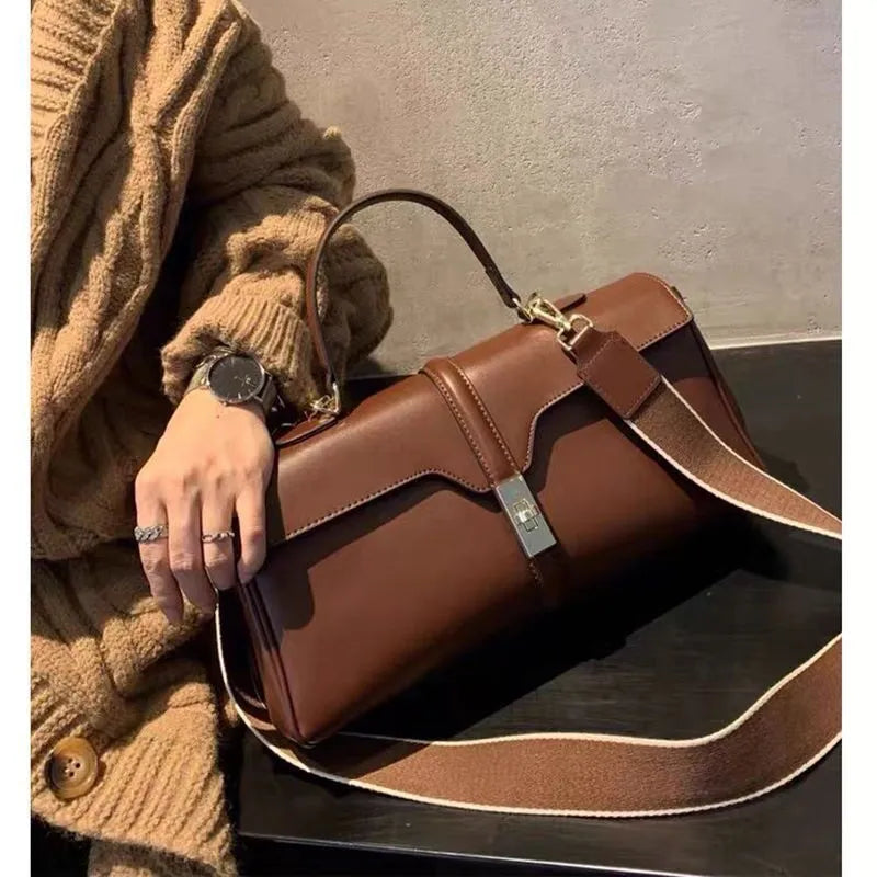 Women's solid colour cowhide leather messenger bag in black, cylindrical shape, with crossbody strap