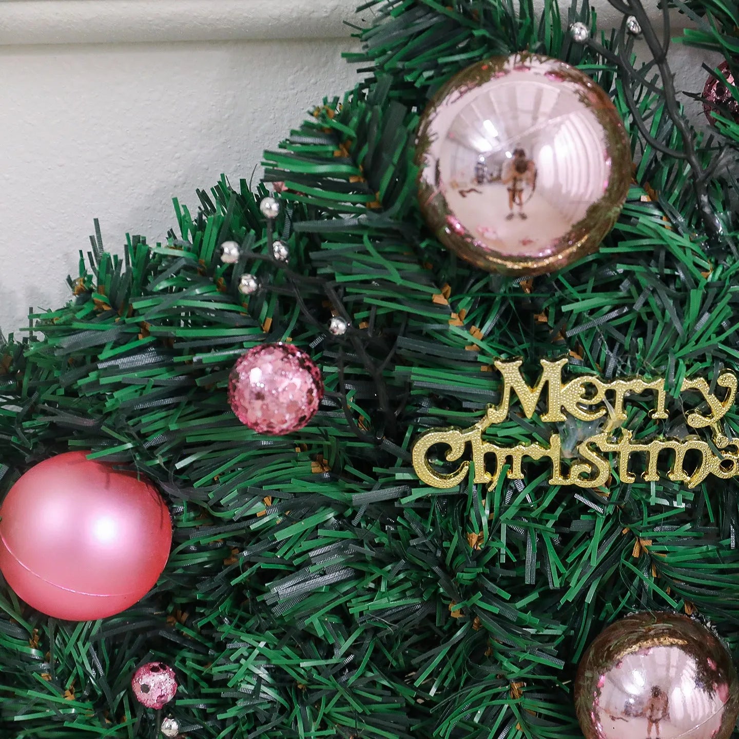 2.7 metre long pink artificial Christmas rattan vine decoration with small berries and leaves against a wall.