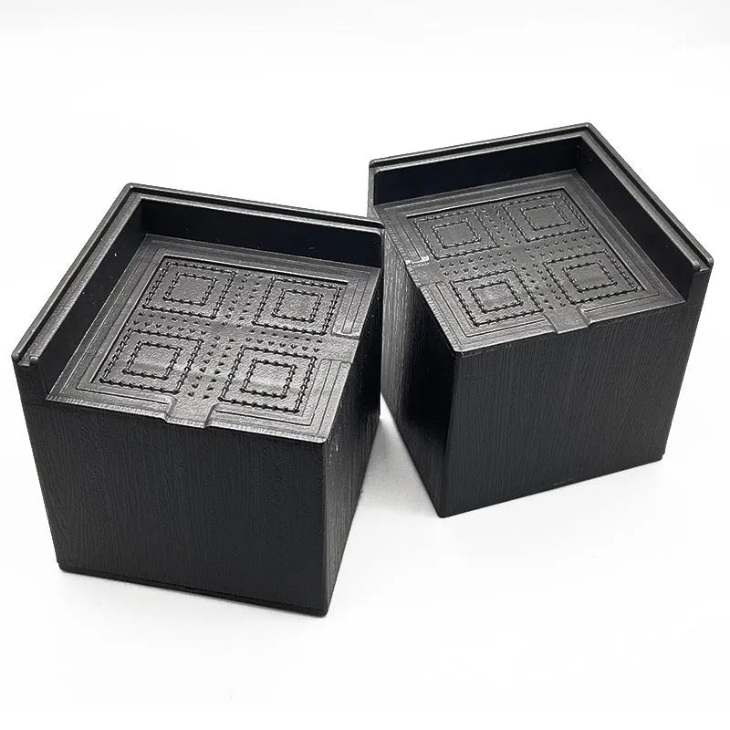 Set of four black thickened plastic bed foot mats for furniture height adjustment.