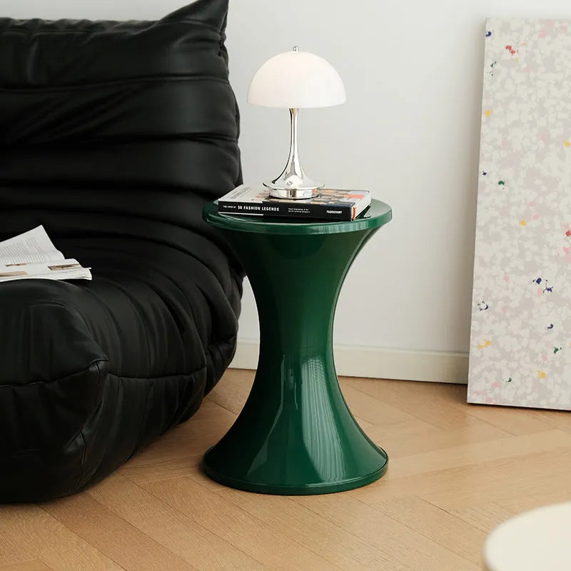 Hourglass-shaped plastic stool in green for changing shoes, used by an adult and child.