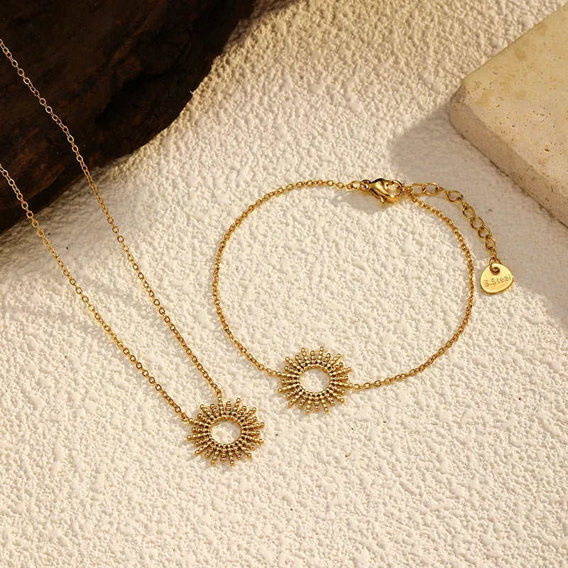 Women's gold geometric sunflower chain necklace and bracelet set on white background