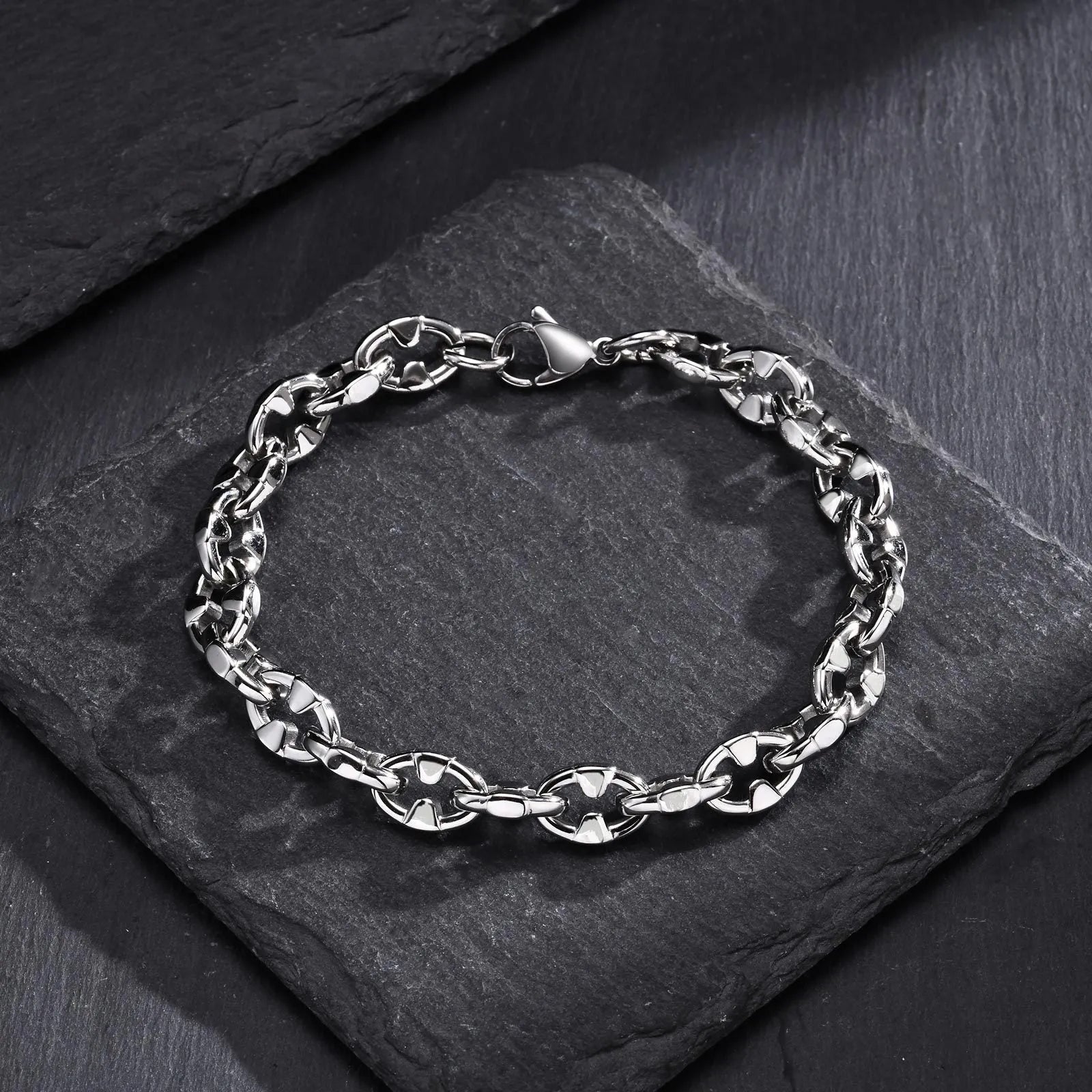 A thick geometric chain bracelet made from stainless steel in a steel colour, shown on a wrist.