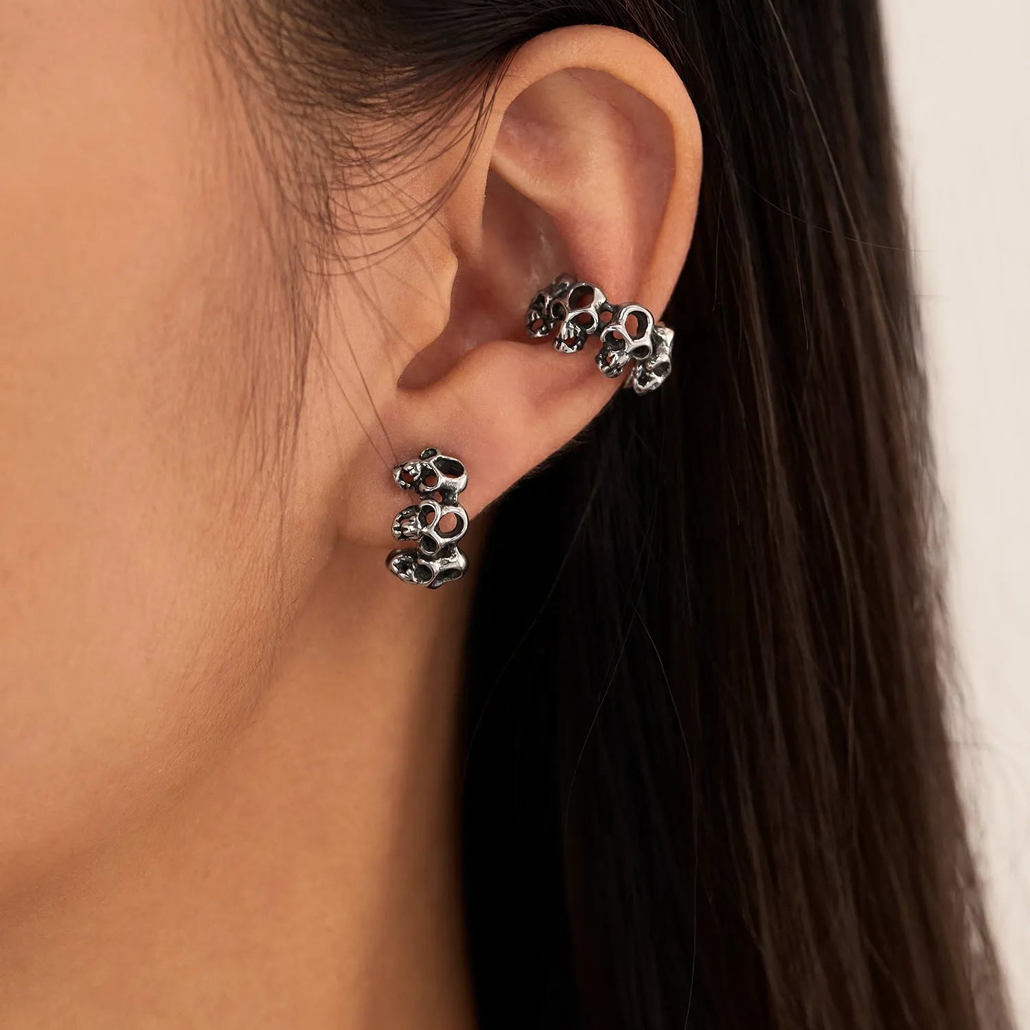Stainless steel clip-on earrings with a hollow geometric skull design.