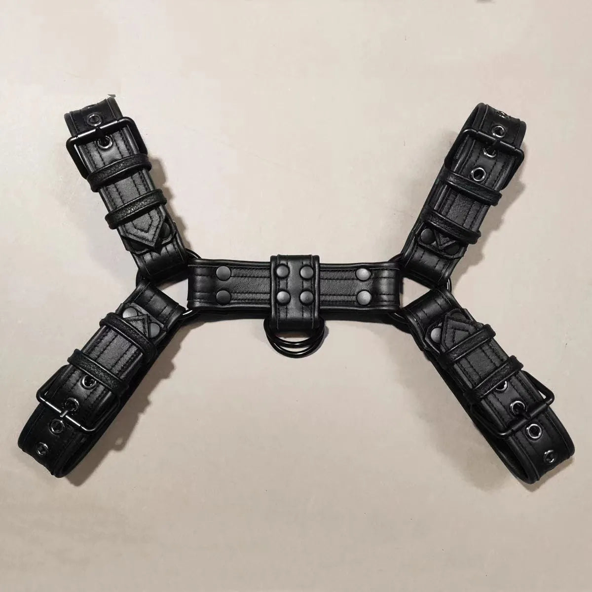 Black leather chest muscle bondage strap with silver metal buckles and rivets laid flat.