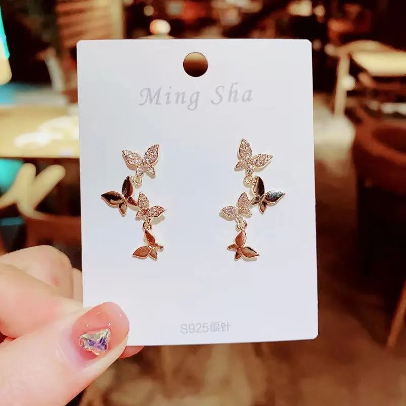 Women's copper butterfly drop earrings with gold finish showing four butterfly design