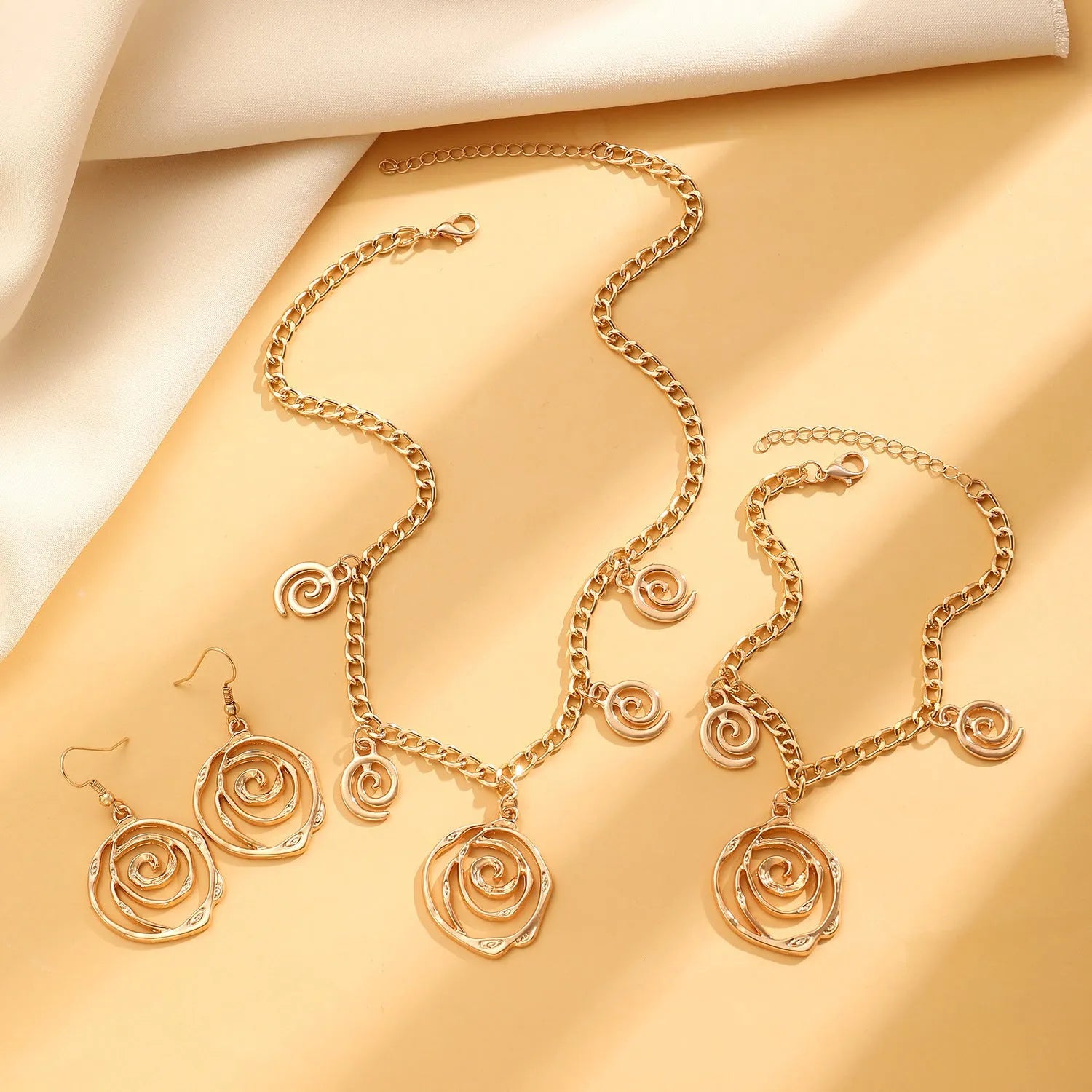Women's spiral donut jewellery set showing necklace, bracelet and earrings in gold alloy finish