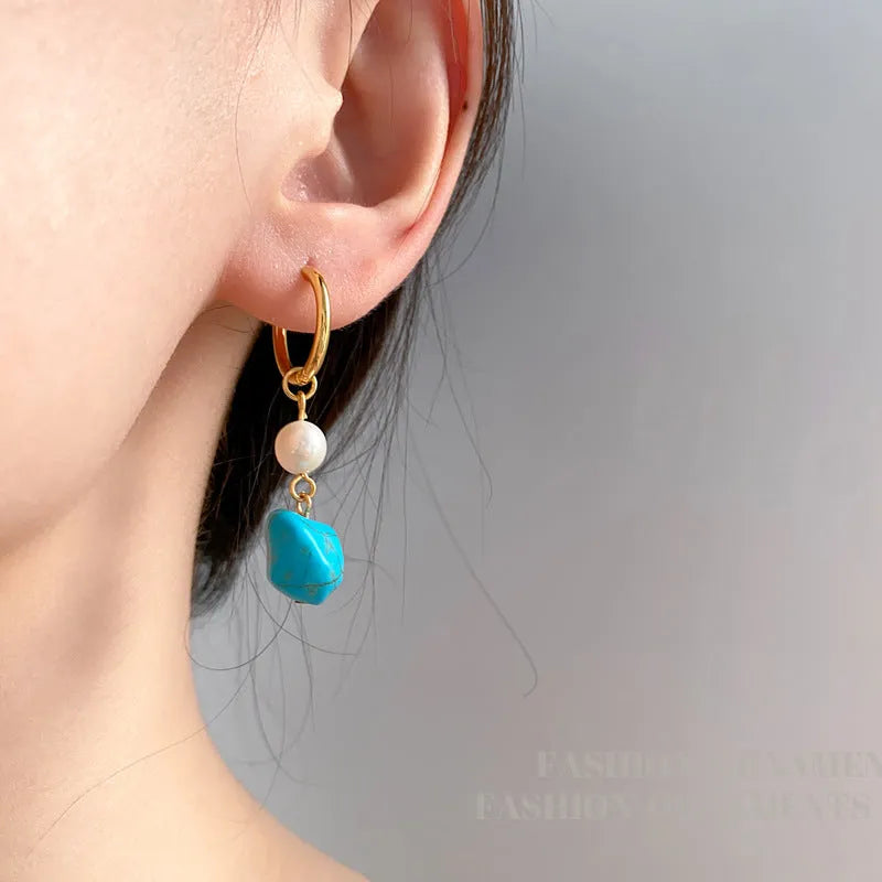 A pair of geometric turquoise and cultured pearl clip-on earrings on a copper setting.