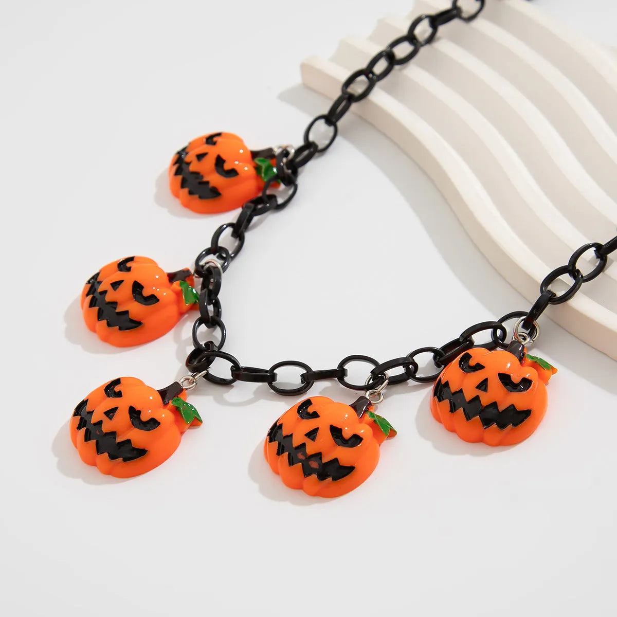 Halloween necklace showing a cartoon ghost and pumpkin acrylic pendant on a metal chain, in mixed colours.