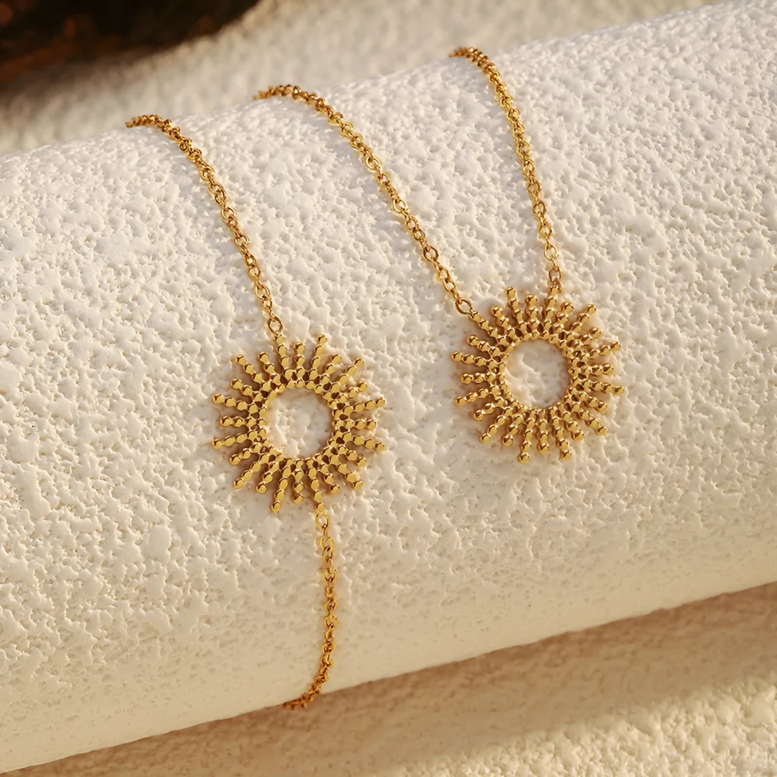 Women's gold geometric sunflower chain necklace and bracelet set on white background