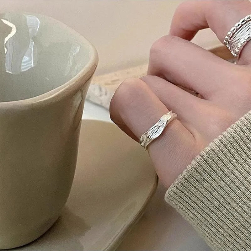 Close-up of a copper ring with a woven twisted geometric multilayer design on a model's hand.