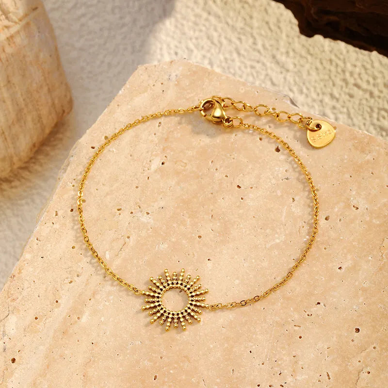 Women's gold geometric sunflower chain necklace and bracelet set on white background