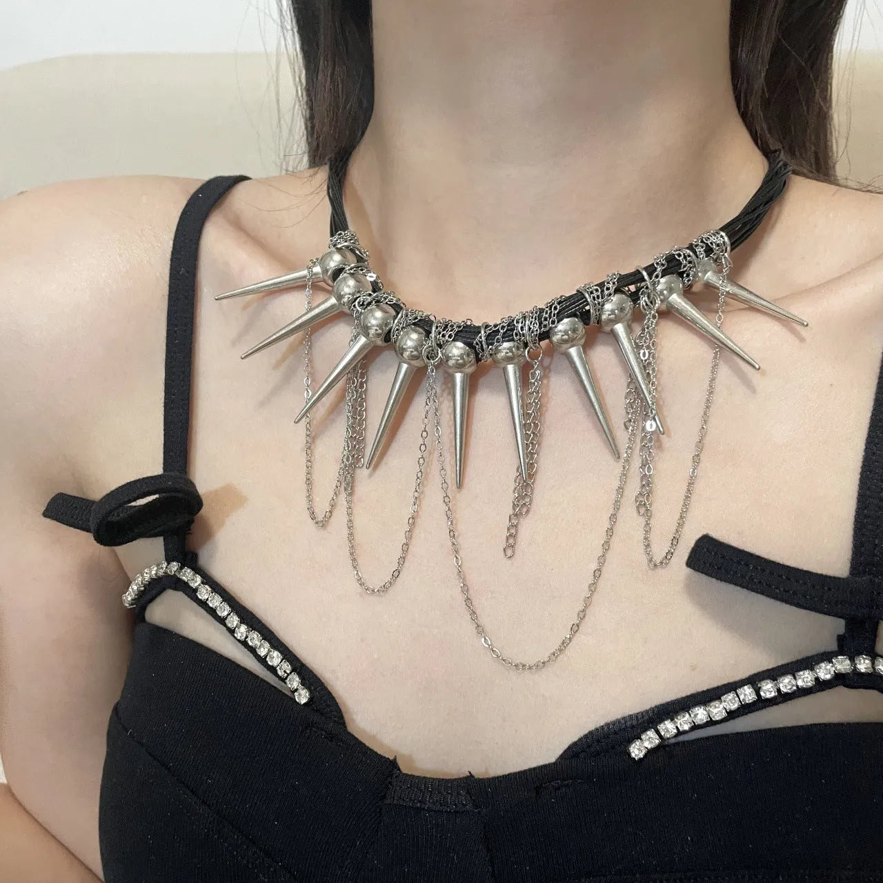 Leather necklace with winding round beads, tassel detail, and electroplated point rivets in casual style.