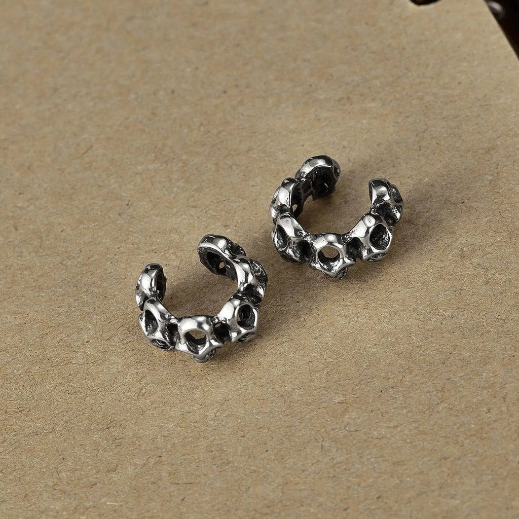 Stainless steel clip-on earrings with a hollow geometric skull design.