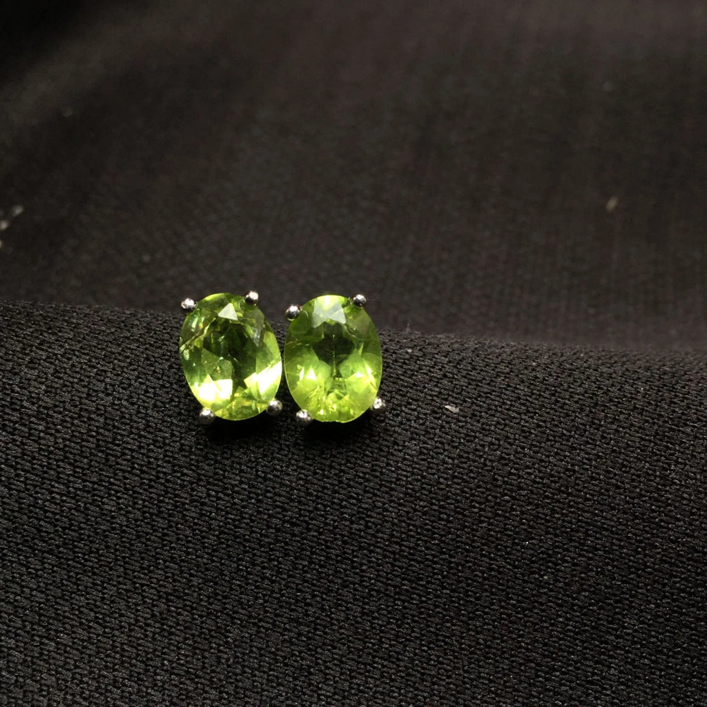 Natural grass green olivine faceted stud earrings in S925 sterling silver on a white background.