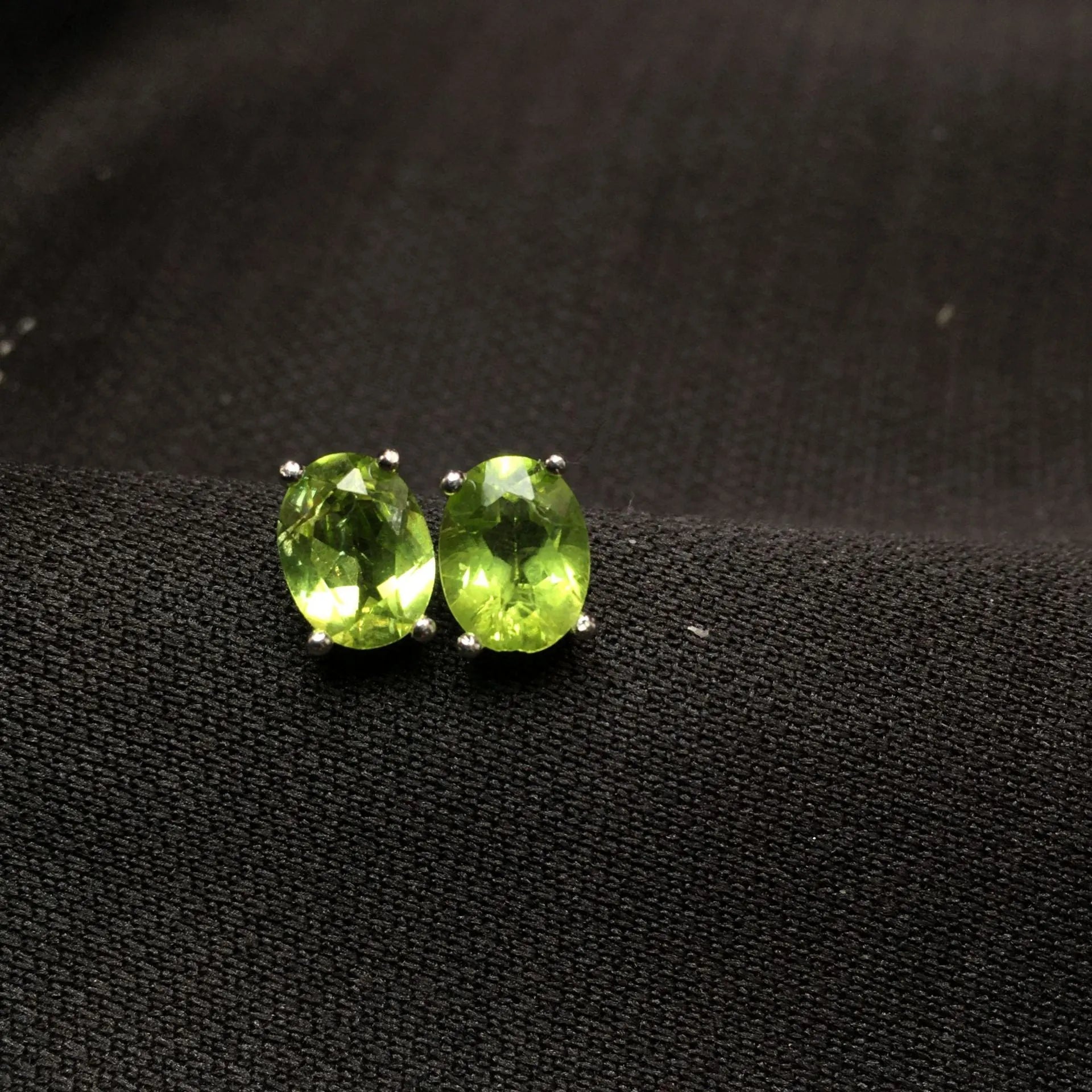 Natural grass green olivine faceted stud earrings in S925 sterling silver on a white background.