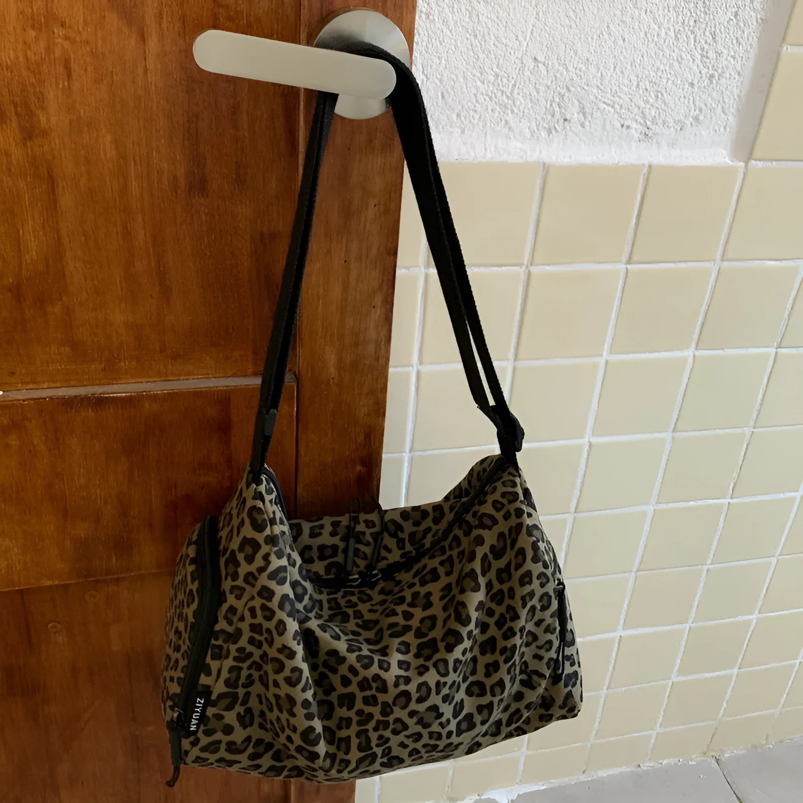 Sports style messenger bag in leopard print pattern with visible stitching and cross-body strap