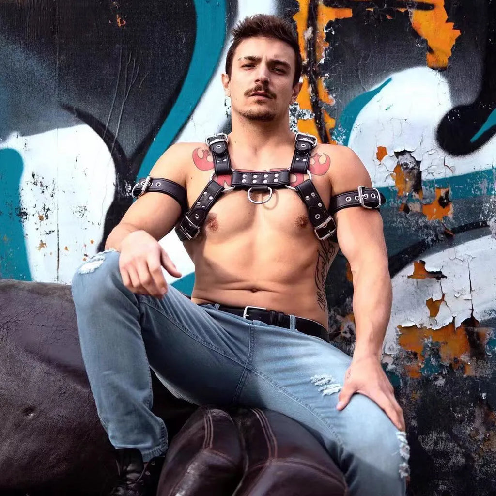 Black leather chest muscle bondage strap with silver metal buckles and rivets laid flat.