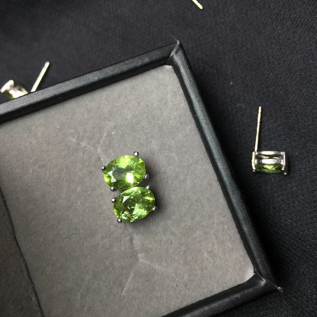 Natural grass green olivine faceted stud earrings in S925 sterling silver on a white background.