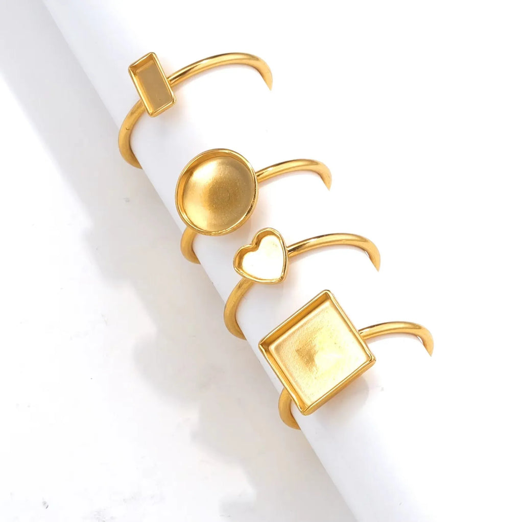 Golden stainless steel ring settings in various shapes including oval, round, square, rectangle, and heart designs
