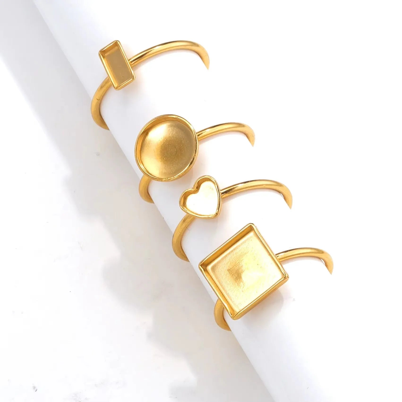 Golden stainless steel ring settings in various shapes including oval, round, square, rectangle, and heart designs