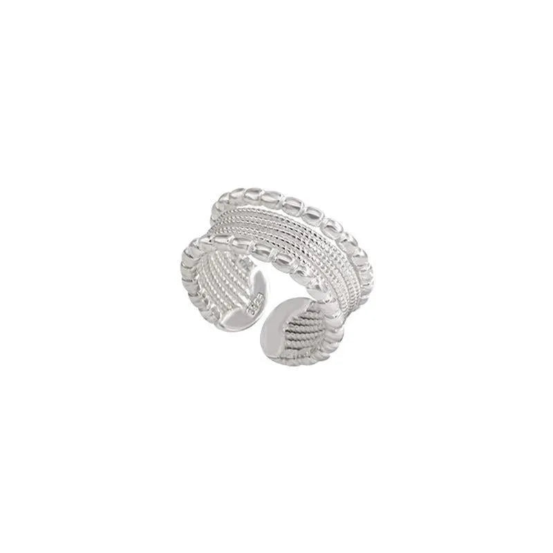 Close-up of a copper ring with a woven twisted geometric multilayer design on a model's hand.