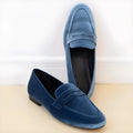 Blue women's slip-on loafers with a black rubber sole, shown in a low-top round toe design.