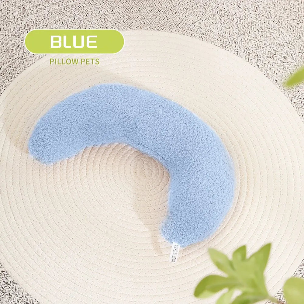 Blue U-shaped cat pillow with an adjustable fabric collar on a grey sofa.