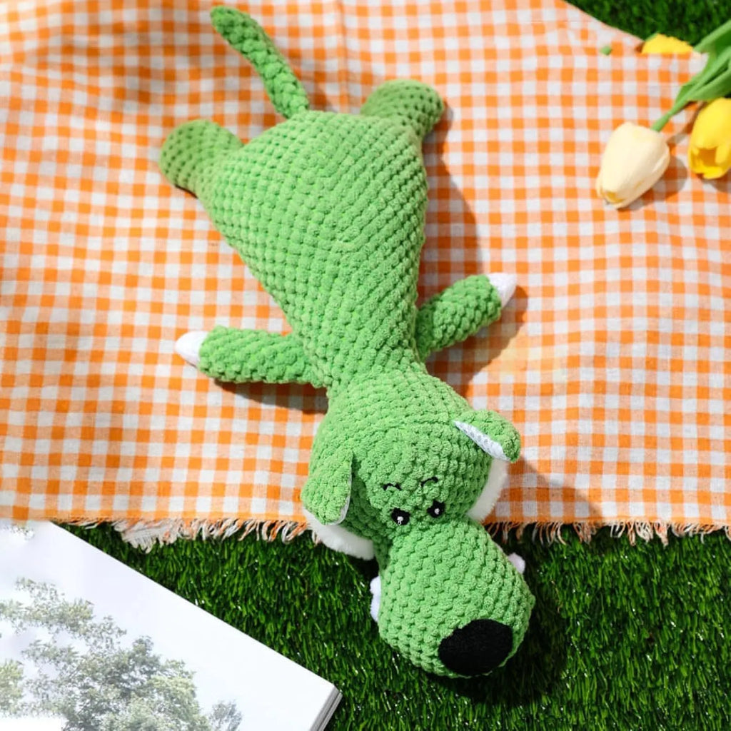 Grey plush dog toy shaped and textured like an ear of corn with visible kernels, lying on a plain surface.