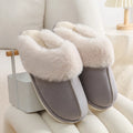 Brown plush indoor slippers with round toe, decorative stitching, and a light-coloured anti-slip sole.