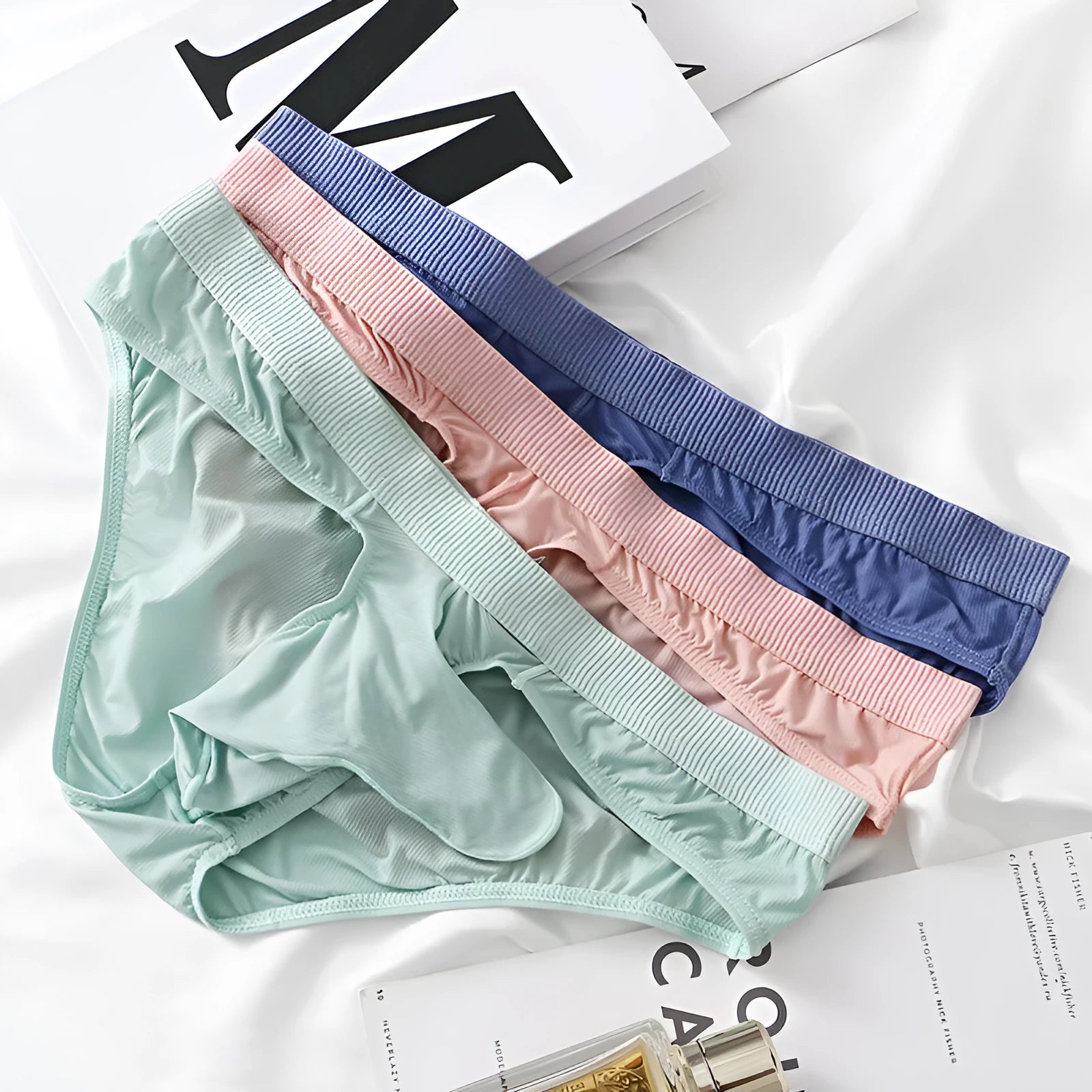 Men's low waist ice silk briefs in multiple colours on a size chart background.