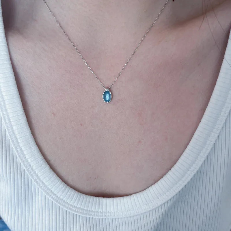 Geometric navy blue and platinum colour water drop pendant necklace on a cross chain.